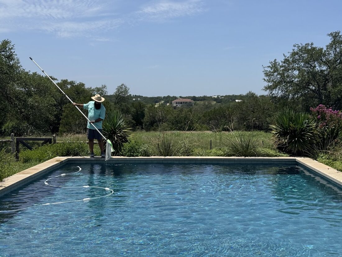 Neptune Reliable Pool Service technician brushing and skimming a backyard pool during weekly maintenance in Tampa, FL